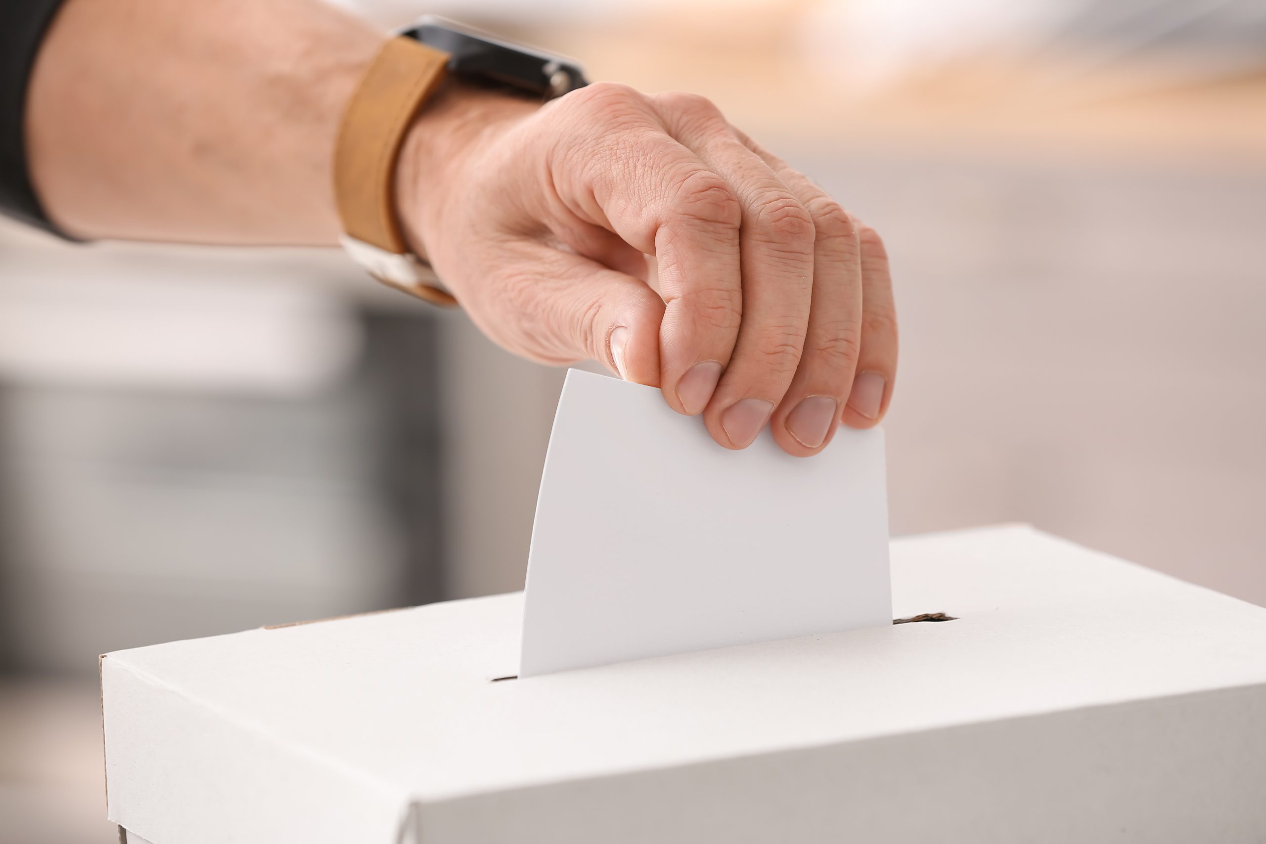 Voting young man near ballot box
